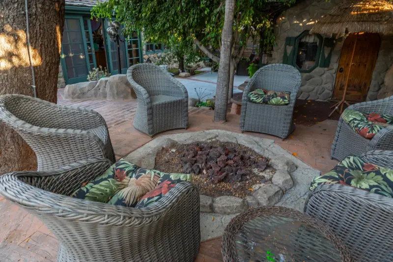 The lava-rock fire pit ringed with wicker chairs at The Enchanted Manor