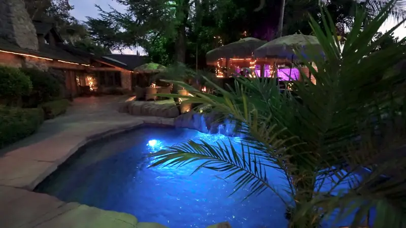 The waterfalls and the pool lit blue at night at The Enchanted Manor
