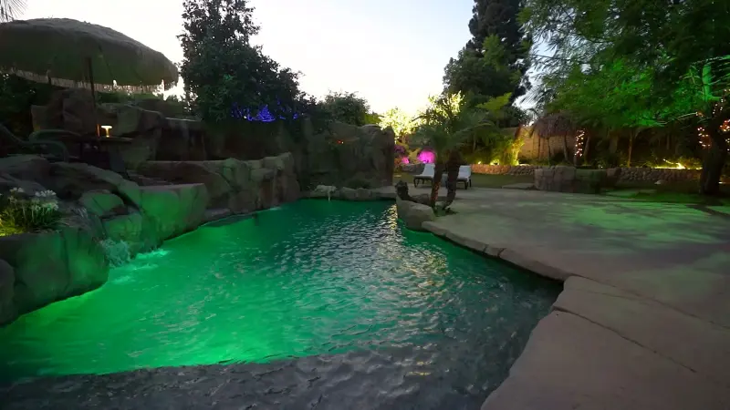 The pool lit emerald green at dusk at The Enchanted Manor