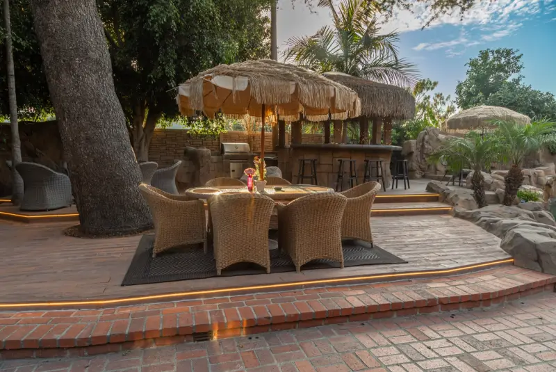 A dining table set beneath the palapas and great tree at The Enchanted Manor